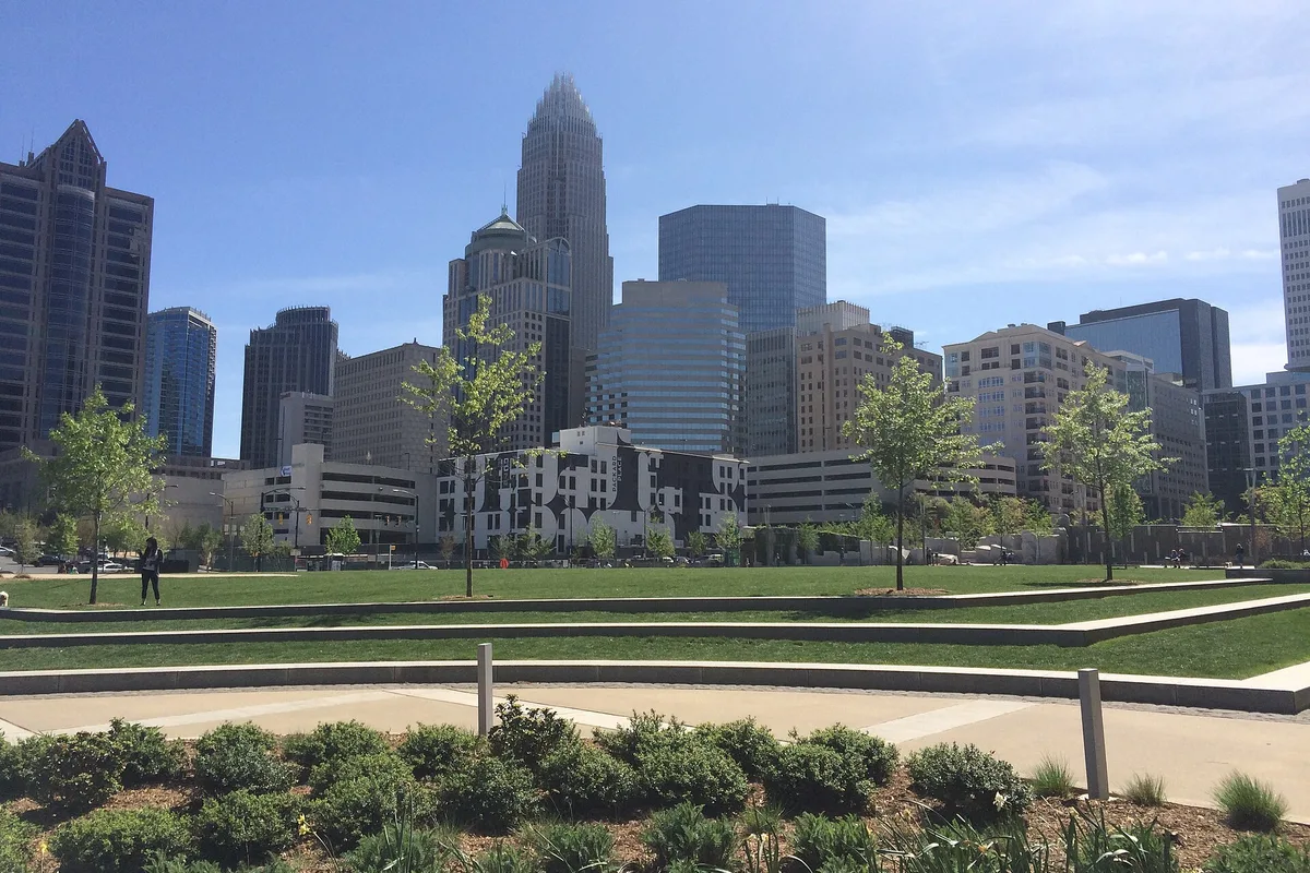 Uptown Charlotte skyline rising beyond the lawn of Romare Bearden Park on a sunny day