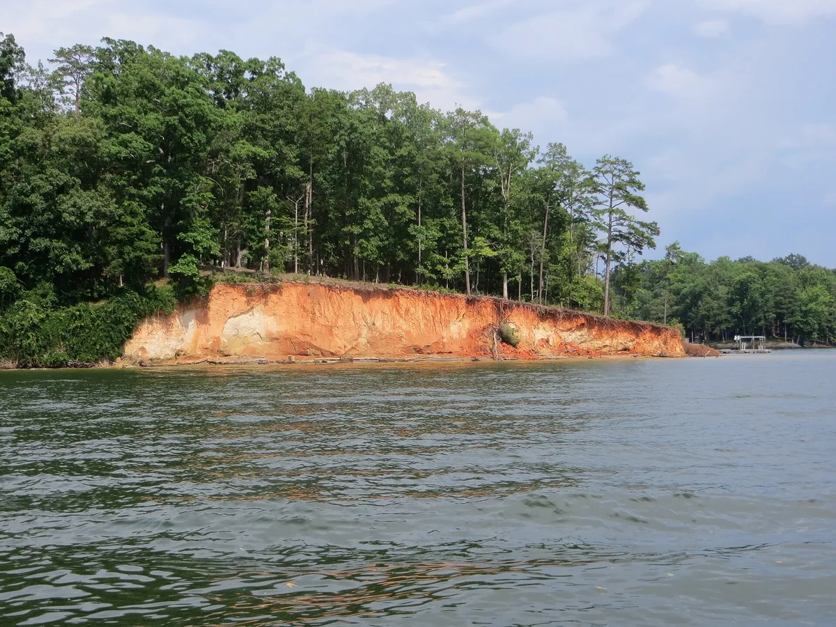 Wooded shoreline with a red clay bank along the water at Lake Wylie