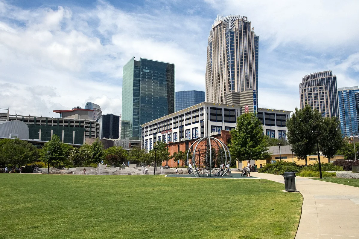 Uptown Charlotte office towers rising behind a green park lawn on a sunny day