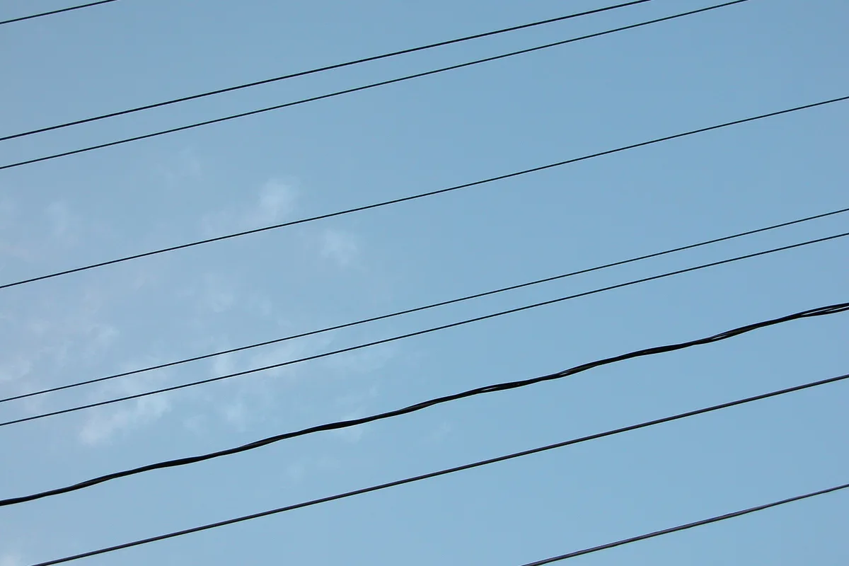 Overhead power lines strung across a clear blue sky