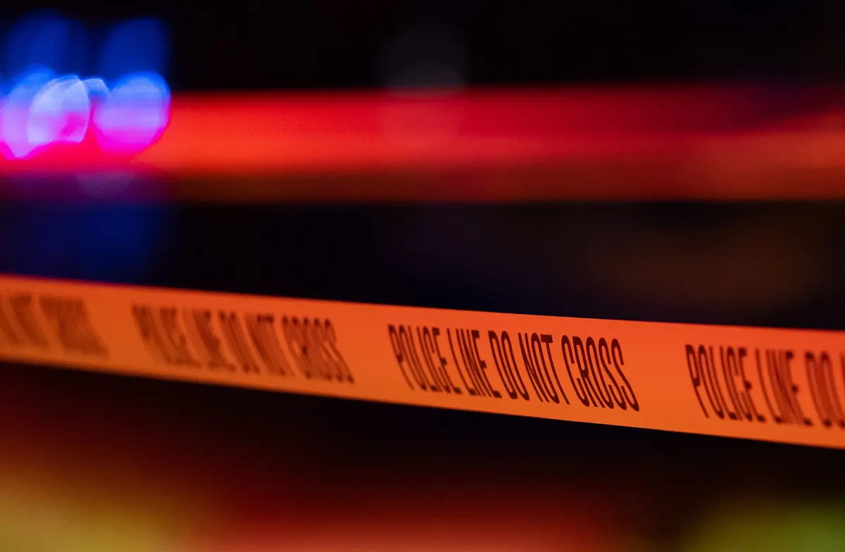 Yellow police line tape at night with blurred emergency lights